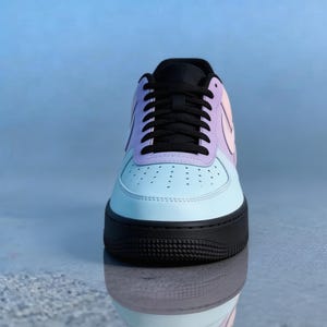 Op de afbeelding: Een pastelkleurige sneaker met een zwarte zool en veters. De schoen heeft een lichtblauwe neus, een lavendelkleurig middengedeelte en een perzikroze hiel. De Nike swoosh is zichtbaar aan de zijkant.
