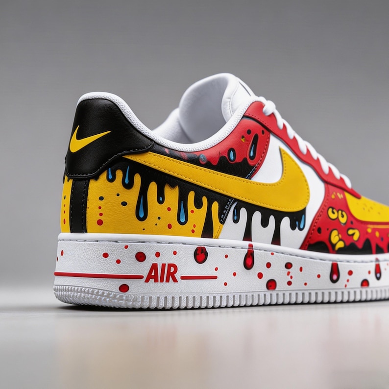 Puede incluir: Una zapatilla Air Force 1 personalizada. La zapatilla presenta una suela blanca con detalles rojos y la palabra "AIR". La parte superior es una mezcla de rojo, amarillo, negro y blanco con un dise&ntilde;o de pintura goteando. Un logo Nike amarillo es visible en el lateral.