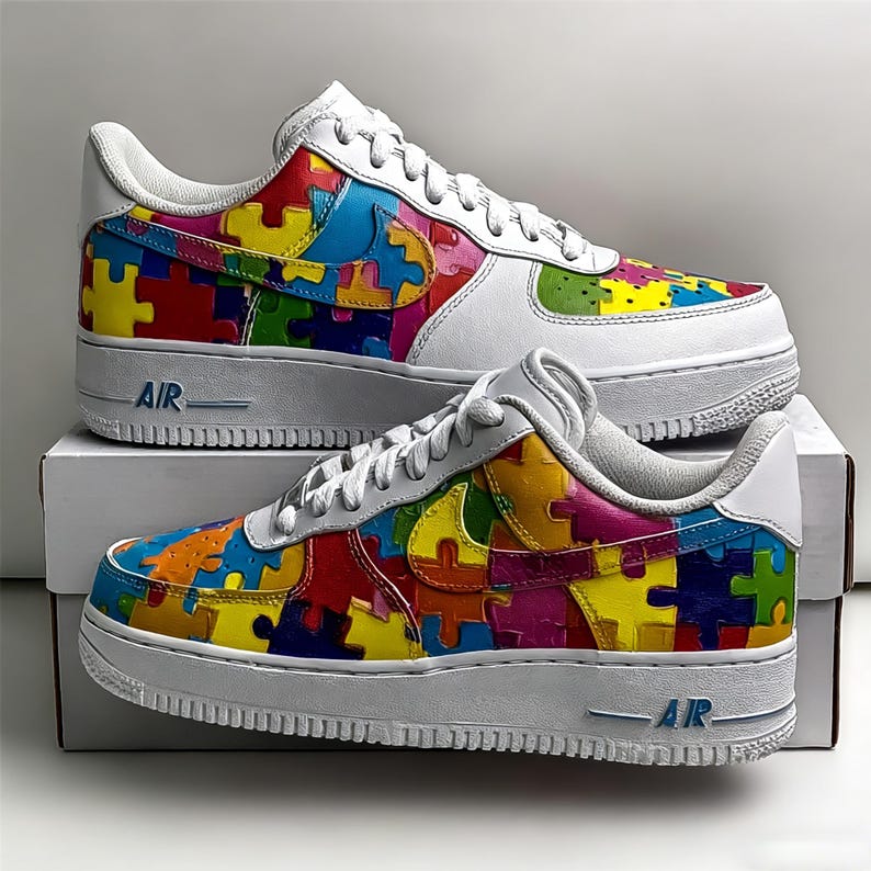 May include: White sneakers with colorful puzzle piece designs. The shoes have a white sole with "AIR" printed on the side. The puzzle pieces are in various colors, including red, yellow, blue, and green.
