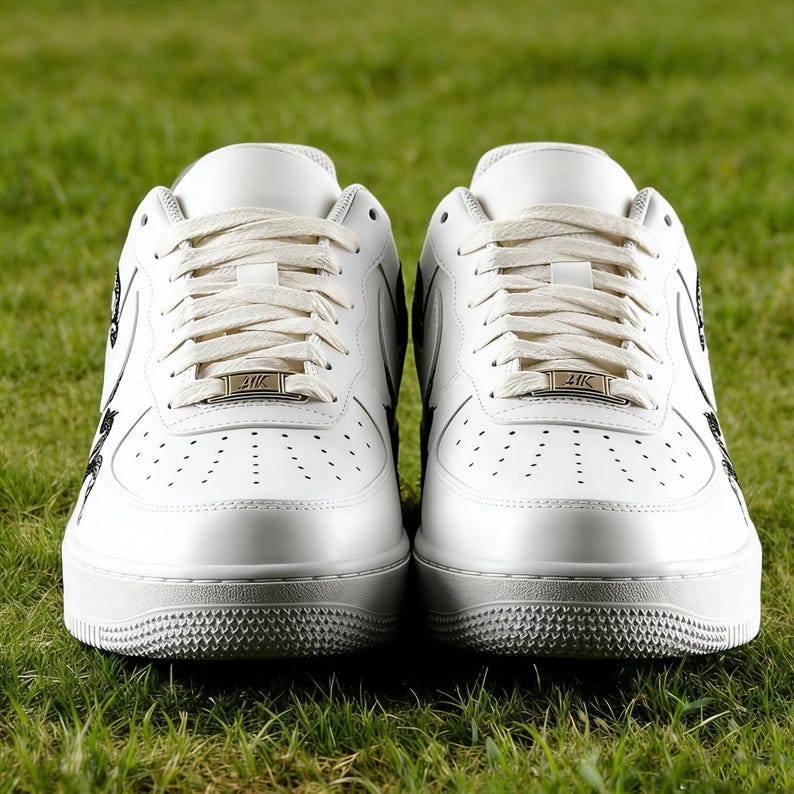 May include: Pair of white leather sneakers with cream-colored laces and a textured sole. The sneakers have a low-top design with perforations on the toe box and black accents. Each shoe features a metallic tag with the text "41K".