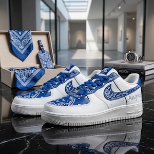May include: White and blue sneakers with a paisley design, blue laces, and the name "Angus" on the side. A matching box set includes a bandana, tag, and necktie. A watch and books are in the background.