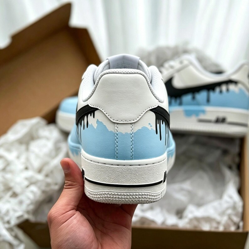 Puede incluir: Zapatillas blancas y celeste con detalles negros. Las zapatillas presentan un dise&ntilde;o &uacute;nico con un efecto de pintura goteando. Las zapatillas est&aacute;n en una caja con papel de seda blanco.