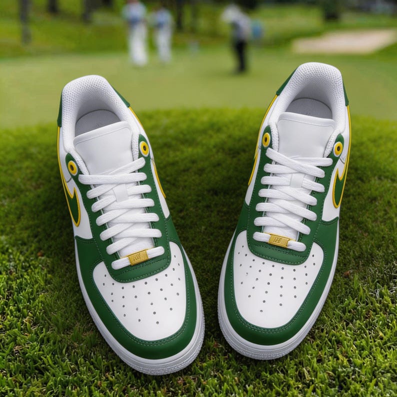 May include: Pair of white, green, and yellow athletic shoes with white laces, set on a green grassy surface. The shoes have a green trim, a yellow swoosh, and a gold accent on the laces. The background is blurred, showing a golf course.