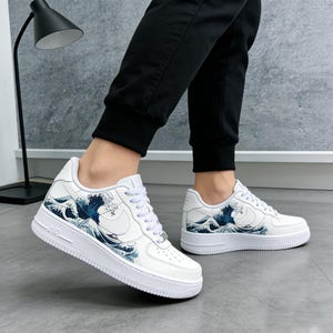 May include: White sneakers with a blue and white wave pattern design. The shoes have a white sole and laces, with the word "AIR" printed on the side. The Nike swoosh logo is visible.