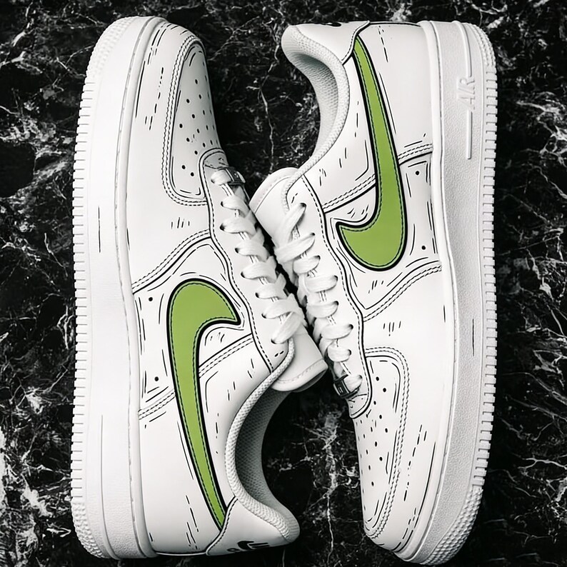 May include: Pair of white sneakers with green swoosh logos and black outline detailing. The shoes have a classic design with a white sole and laces. The sneakers are displayed on a dark, marbled surface.