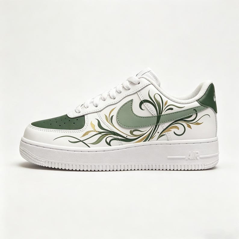 May include: White leather sneaker with green accents and a floral design. The shoe features a green Nike swoosh and a green toe cap. Gold and green floral patterns adorn the side of the shoe. The sole is white with the word "AIR" on the side.