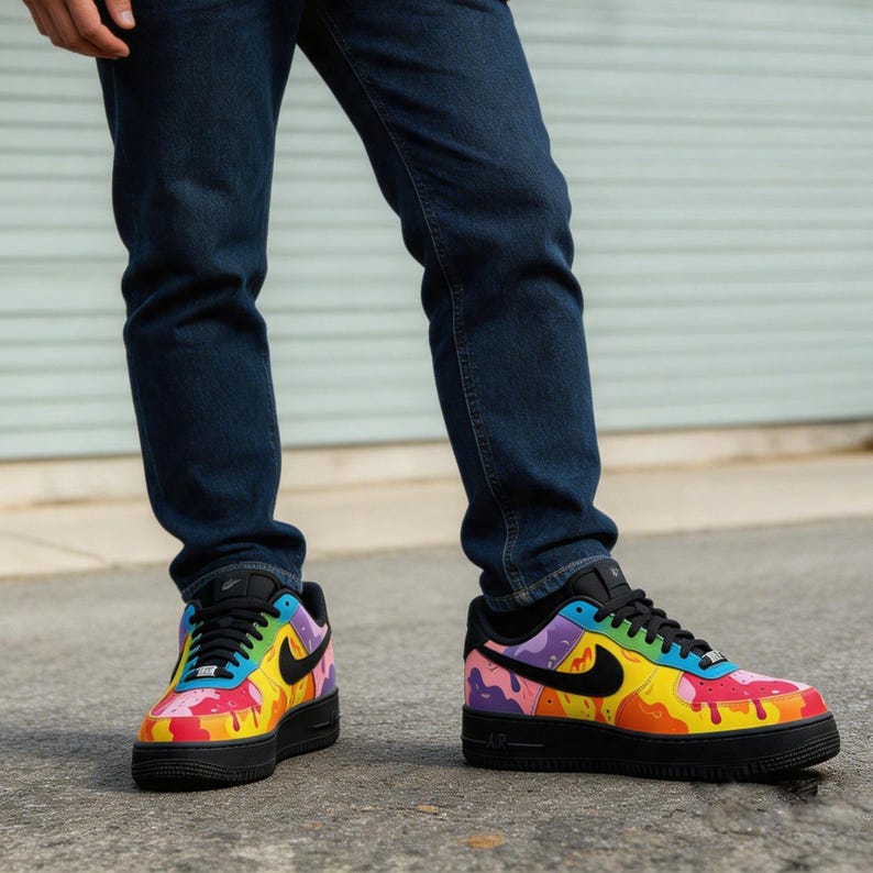 May include: A pair of colorful sneakers with a black sole and laces. The sneakers feature a vibrant design with splashes of red, yellow, blue, and purple, and a black Nike swoosh logo on the side.