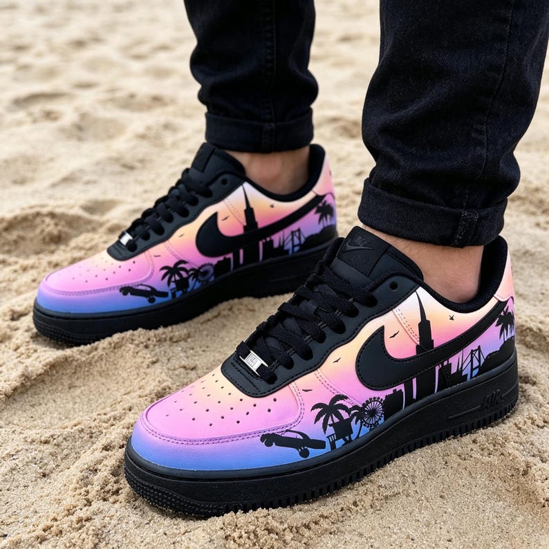 May include: Black and multi-colored sneakers with a cityscape design. The shoes feature a gradient of pink, orange, and blue hues, with a black silhouette of palm trees, buildings, and a car. The Nike swoosh is black.