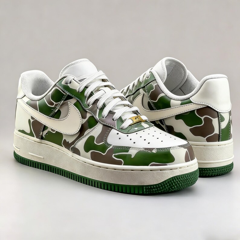 May include: Pair of white, green, and brown camouflage sneakers. The shoes feature a white leather upper with a green and brown camouflage pattern, a white swoosh, and a green sole. The laces are white, and the midsole is off-white.