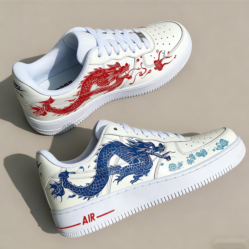 May include: White sneakers with red and blue dragon designs. The shoes feature a classic low-top design with white laces and soles. The word "AIR" is printed in red on the side of the shoe.
