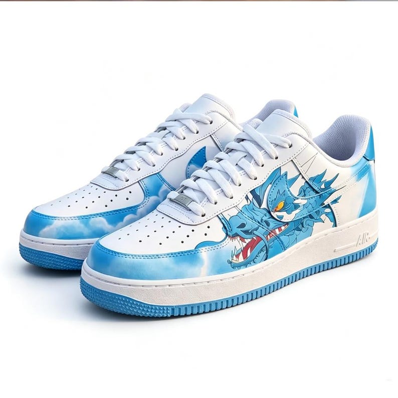 May include: White leather sneakers with blue accents and a dragon design. The shoes feature a blue dragon graphic on the side, cloud patterns, and blue soles. The laces are white, and the shoes have a classic athletic style.