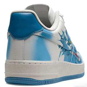 May include: White and blue sneakers with a dragon design. The shoes feature a white base with blue accents on the heel and sole. A detailed blue dragon graphic adorns the side, with red and yellow details. The sole is approximately 1 inch thick.