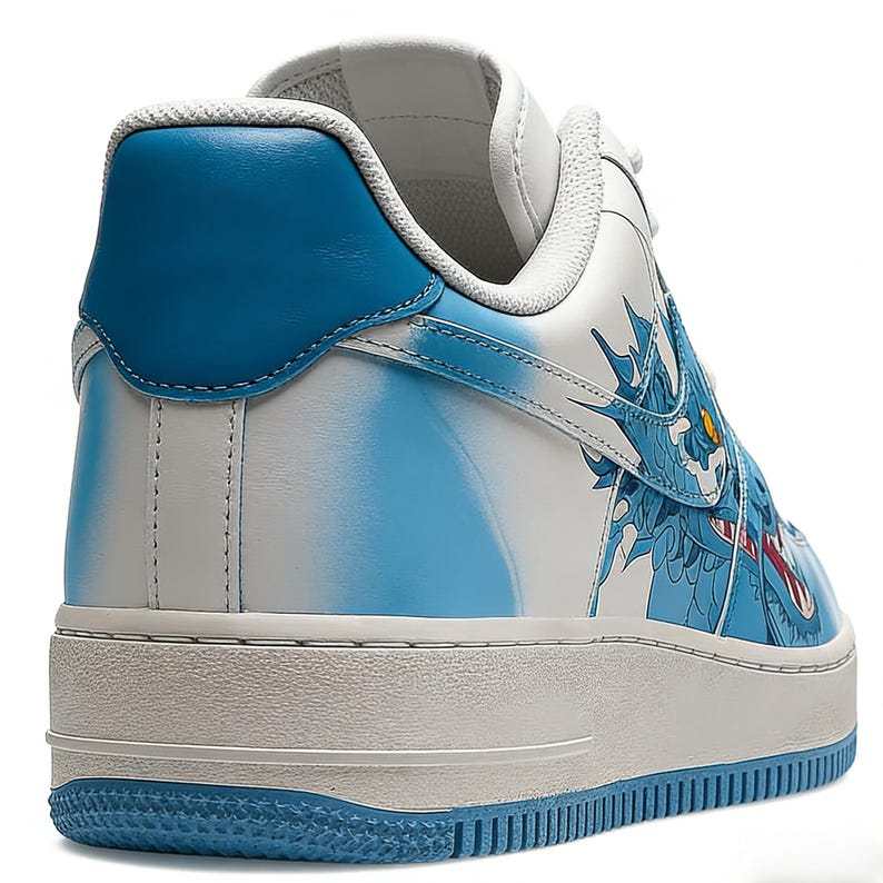 May include: White and blue sneakers with a dragon design. The shoes feature a white base with blue accents on the heel and sole. A detailed blue dragon graphic adorns the side, with red and yellow details. The sole is approximately 1 inch thick.