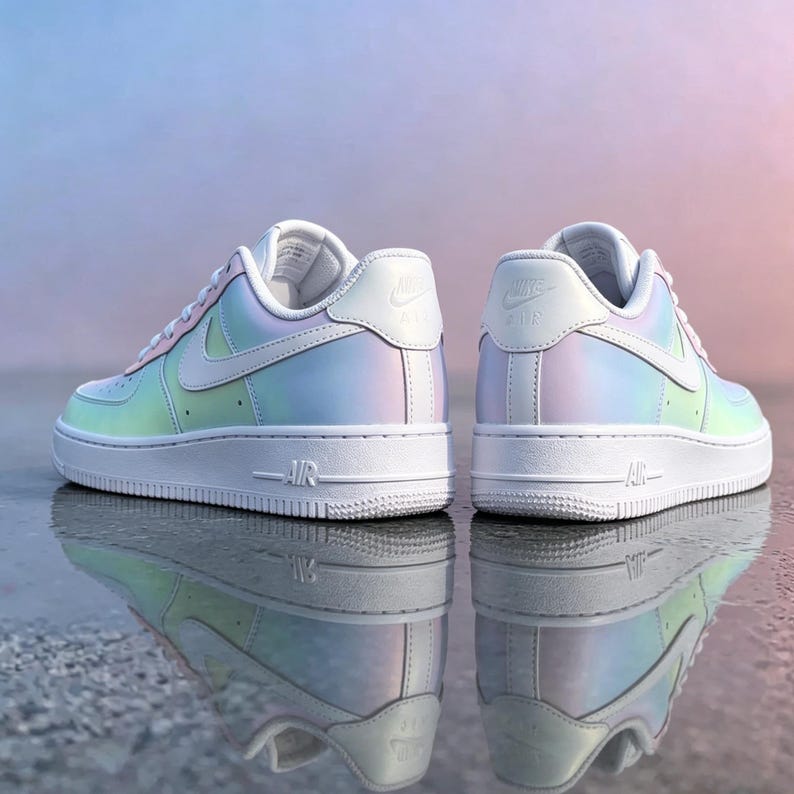May include: Two iridescent sneakers with white accents and soles are displayed. The sneakers have a pearlescent finish that reflects colors like blue, green, and pink. The Nike logo is visible on the side and heel of each shoe.