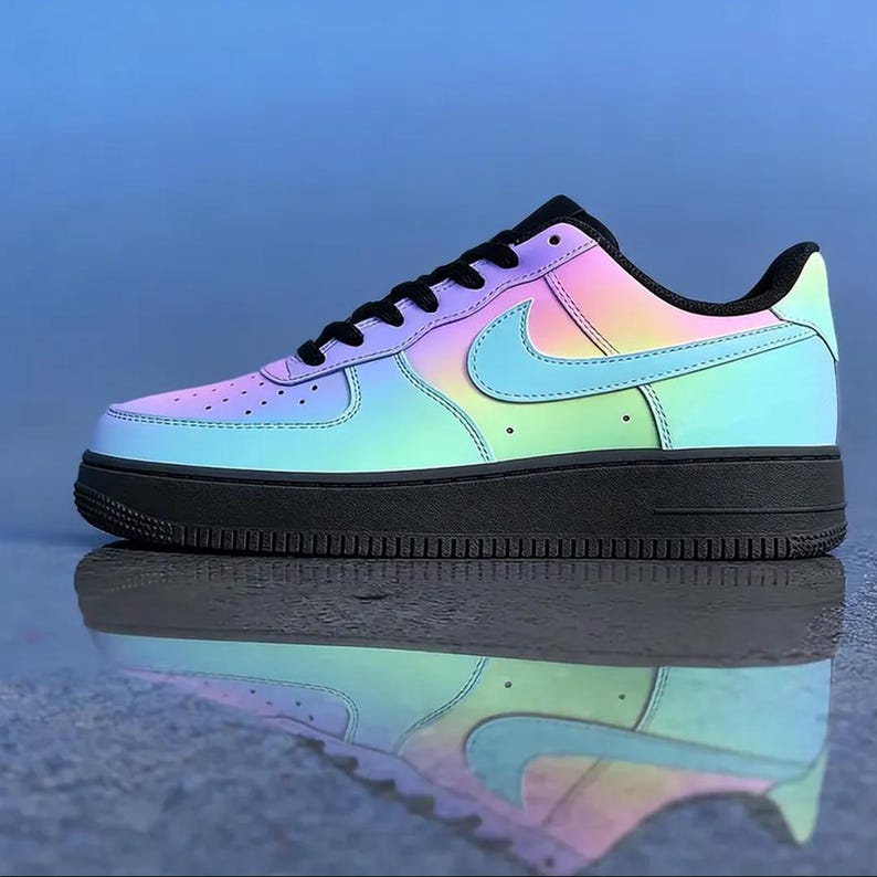 May include: A colorful Air Force 1 sneaker with a gradient design. The shoe features a black sole and laces, with a rainbow-colored upper that transitions from pink to blue and green. The Nike swoosh is light blue.