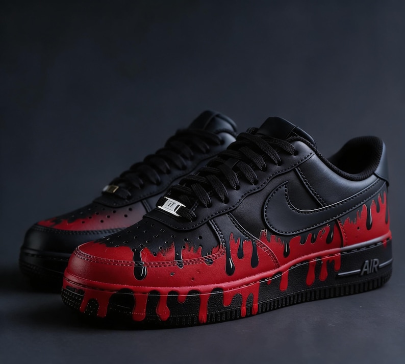 May include: Pair of black and red Air Force 1 sneakers. The shoes have a black upper with a red base and dripping paint design. The Nike swoosh is visible on the side. The laces are black.