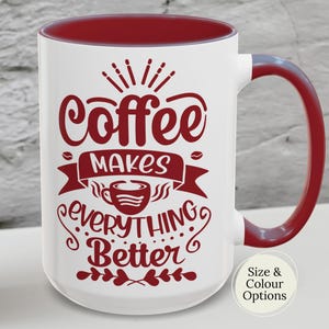 May include: A white ceramic mug with a black handle and the text "But First, Coffee" in a bold, black font. The mug is set against a blurred background, suggesting a cozy setting.