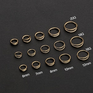 May include: A collection of gold-colored double-hoop earrings in various sizes, including 6mm, 7mm, 8mm, 10mm, and 12mm, as well as 20G, 18G, and 16G gauges. The earrings are arranged on a dark surface, showcasing their design.