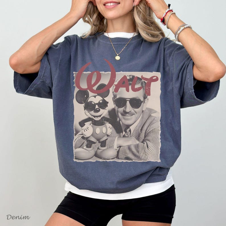 May include: A dark blue oversized t-shirt featuring a graphic print of Walt Disney and Mickey Mouse both wearing sunglasses. The text "Walt" is printed in a large, stylized red font above the black and white image of the two characters.