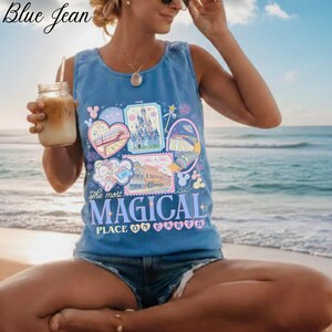 Pu&ograve; includere: Canotta azzurra con grafica colorata raffigurante varie attrazioni di parchi a tema e la scritta "The most MAGICAL PLACE ON EARTH". La parte superiore &egrave; abbinata a pantaloncini di jeans. Le parole "Blue Jean" sono nell'angolo in alto a sinistra.