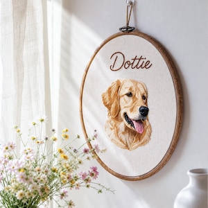 Könnte beinhalten: Ein runder Stickrahmen aus Holz mit einer cremefarbenen Stoffbespannung. Der Stoff zeigt ein detailliertes, gesticktes Porträt eines Golden Retrievers mit herausgestreckter Zunge und den Namen Dottie in brauner Schreibschrift darüber.