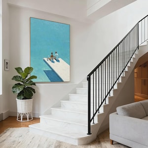 May include: An oil painting depicts two figures on a white diving board over a blue pool. The artwork hangs on a white wall above a staircase with black railings. A large potted plant sits near the stairs.