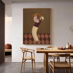 May include: A framed wall art print featuring a stylized illustration of a person wearing a white hat, a pink long-sleeved shirt, a dark vest, and light-colored trousers, holding a small brown dog overhead against a brown and diamond-patterned floor.
