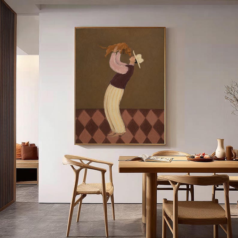 May include: A framed wall art print featuring a stylized illustration of a person wearing a white hat, a pink long-sleeved shirt, a dark vest, and light-colored trousers, holding a small brown dog overhead against a brown and diamond-patterned floor.