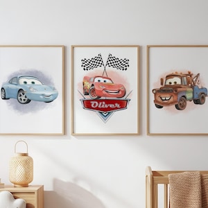 Può includere: Tre stampe incorniciate con auto dei cartoni animati. La prima mostra un'auto azzurra, la seconda un'auto rossa con il nome "Oliver" e la terza un carro attrezzi marrone. Ogni stampa ha uno sfondo in stile acquerello.
