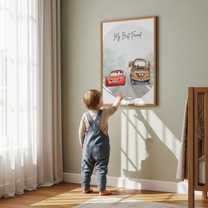May include: A framed print featuring the characters Lightning McQueen and Mater from the movie Cars, with the text "My Best Friend." A young child in denim overalls reaches toward the artwork, which hangs on a light green wall.