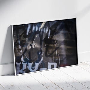 Könnte beinhalten: Ein gerahmter Kunstdruck mit abstrakten Graffiti in Schwarz, Weiß und Grau. Das Kunstwerk hat einen kühnen, grafischen Stil, wobei das Wort "HOLD" in weißen Blockbuchstaben sichtbar ist. Der Druck lehnt an einer weißen Wand auf einem Holzboden.