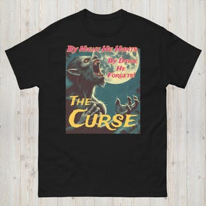 May include: Black t-shirt featuring a vintage-style werewolf graphic. The design includes a howling werewolf under a full moon, with the text "By Night He Hunts, By Dawn He Forgets!" and "The Curse" in a retro font.