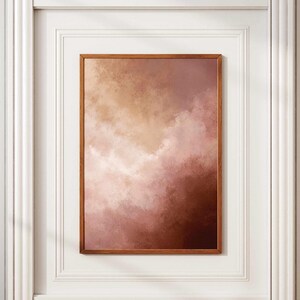 Peut inclure: Une impression d'art abstrait encadrée avec un mélange de couleurs chaudes. L'œuvre présente un dégradé de beige clair, de rose et de brun foncé, ressemblant à un ciel nuageux. L'impression est encadrée dans un cadre en bois brun simple, pour la décoration intérieure.