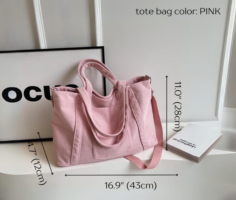 May include: Pink corduroy tote bag with a shoulder strap and handles. The bag is 16.9 inches (43cm) wide, 11.0 inches (28cm) tall, and 4.7 inches (12cm) deep. The text "tote bag color: PINK" is visible.
