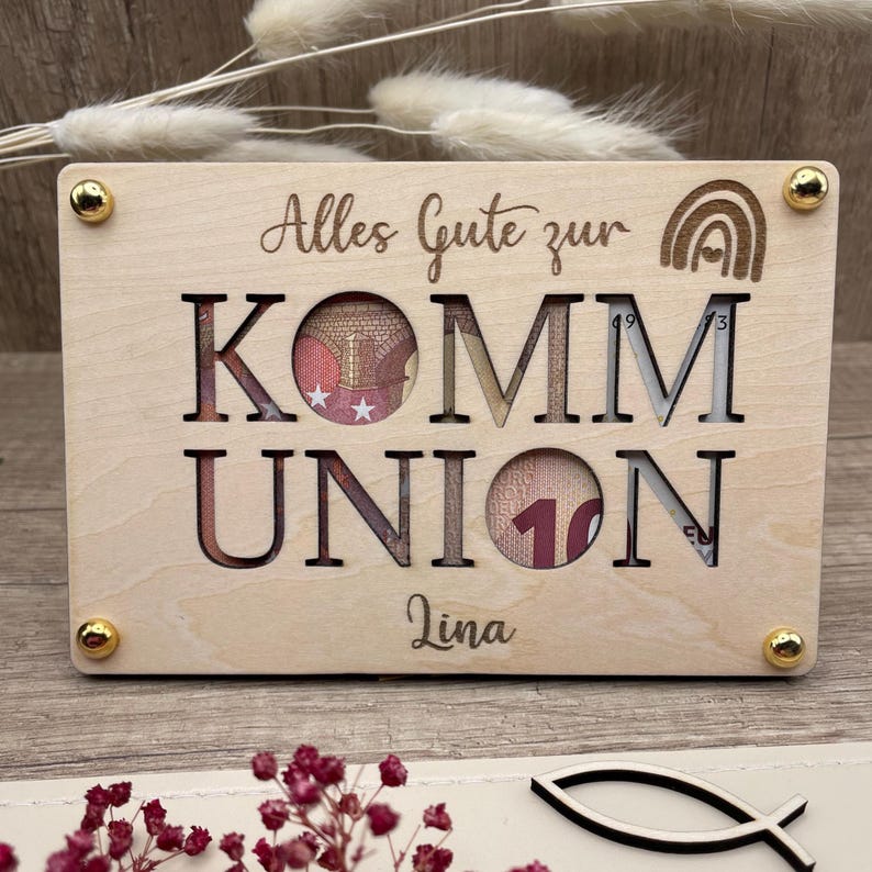 Geldgeschenk zur Kommunion und eine ausgefallene Geschenkidee in Form einer gravierten Holzkarte die auf einer zweite Holzkarte befestigt wird. Zwischen den Karten entsteht so Platz für Geldschein, Gutschein oder Botschaften. Es werden vier Symbole graviert angeboten: Christenfisch, Regenbogen, Taube und Ölzweig als Kranz um den personalisierten Namen.