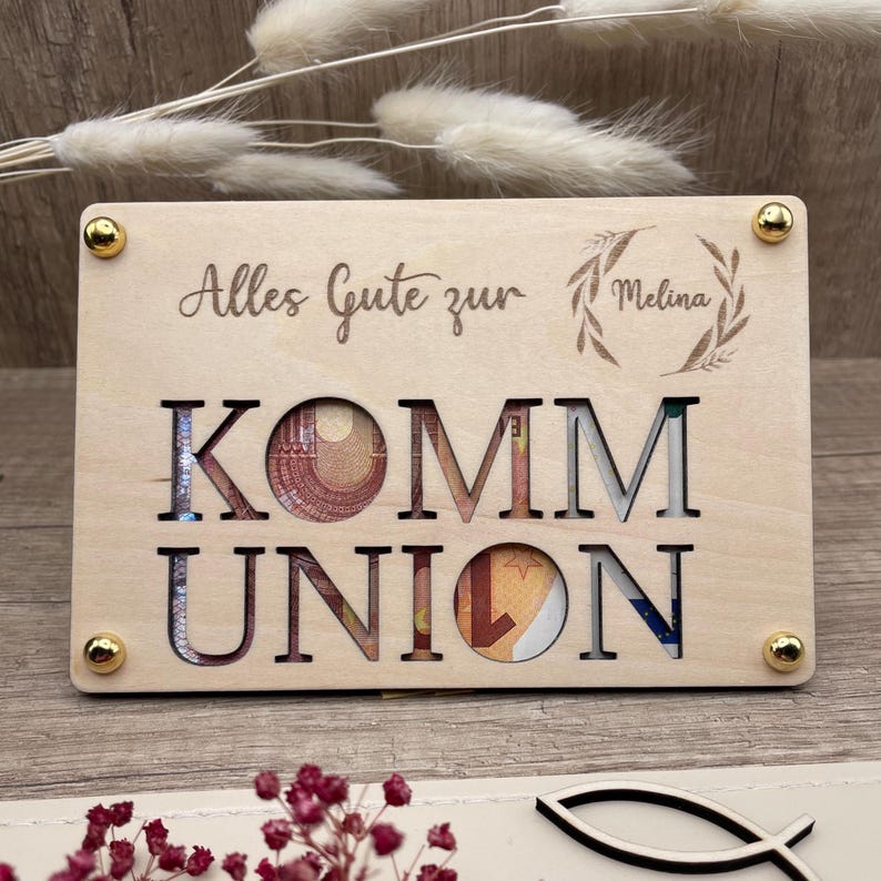 Geldgeschenk zur Kommunion und eine ausgefallene Geschenkidee in Form einer gravierten Holzkarte die auf einer zweite Holzkarte befestigt wird. Zwischen den Karten entsteht so Platz für Geldschein, Gutschein oder Botschaften. Es werden vier Symbole graviert angeboten: Christenfisch, Regenbogen, Taube und Ölzweig als Kranz um den personalisierten Namen.