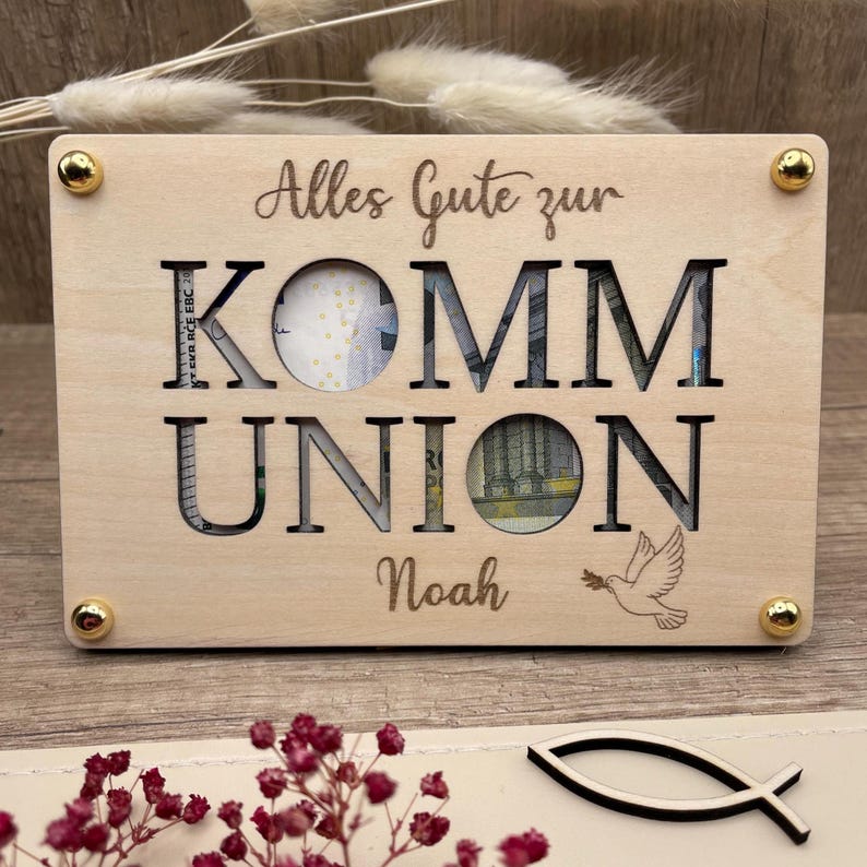 Geldgeschenk zur Kommunion und eine ausgefallene Geschenkidee in Form einer gravierten Holzkarte die auf einer zweite Holzkarte befestigt wird. Zwischen den Karten entsteht so Platz für Geldschein, Gutschein oder Botschaften. Es werden vier Symbole graviert angeboten: Christenfisch, Regenbogen, Taube und Ölzweig als Kranz um den personalisierten Namen.