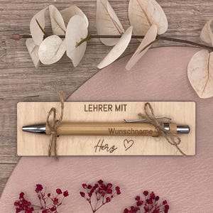 LehrerIn mit Herz mit Holztafel und Wunschname auf Kugelschreiber