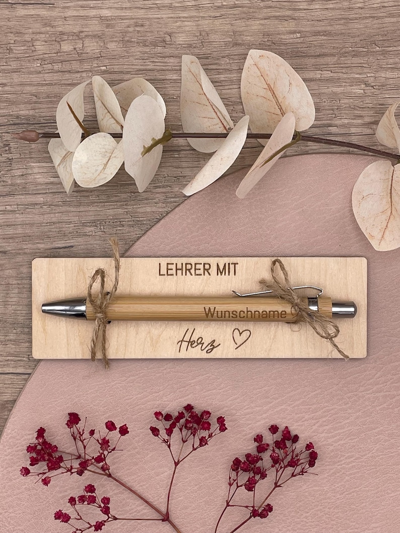LehrerIn mit Herz mit Holztafel und Wunschname auf Kugelschreiber