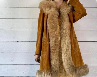 May include: A vintage brown suede coat with a faux fur collar, trim, and cuffs. The coat has a long, flowing design with a button closure and two front pockets. The coat is a warm, stylish outerwear piece.