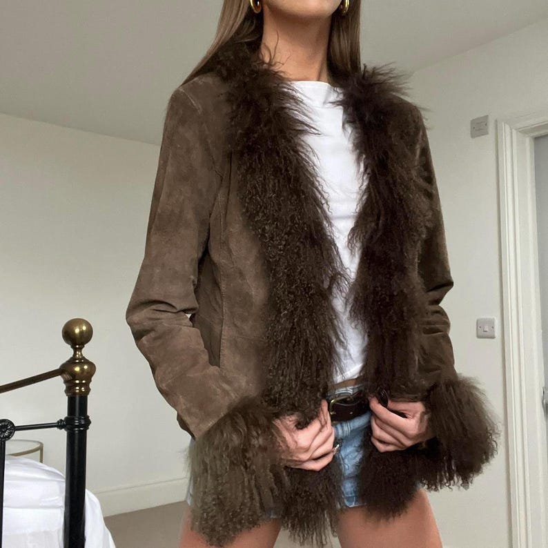 Puede incluir: Chaqueta de ante marr&oacute;n con ribete de piel sint&eacute;tica alrededor del cuello y los pu&ntilde;os. La chaqueta tiene un dise&ntilde;o cl&aacute;sico con un corte entallado. El ribete de piel a&ntilde;ade un toque de lujo y calidez. Una prenda vers&aacute;til.