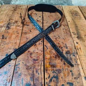 Può includere: Tracolla per chitarra in pelle nera con motivi floreali e geometrici in rilievo. Fibbia e dettagli decorativi color argento. La tracolla ha un cuscinetto imbottito per la spalla ed è progettata per chitarre elettriche o acustiche.