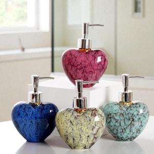 May include: Heart-shaped ceramic soap dispensers in shades of blue, yellow, teal, and pink. Each dispenser has a silver pump and a glossy finish. These decorative dispensers add a touch of elegance to any bathroom or kitchen.