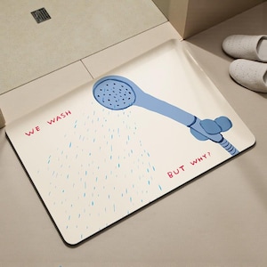 Può includere: Un tappetino da bagno rettangolare con un'illustrazione di soffione blu e la scritta "WE WASH BUT WHY?" in rosso e nero. Il tappetino è bianco con gocce d'acqua blu. Sono visibili due pantofole bianche.