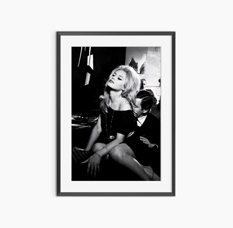 A black and white photograph of a woman sitting on a chair, with a man sitting next to her.