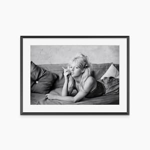 A black and white photograph of a woman lying on a couch, looking pensive.