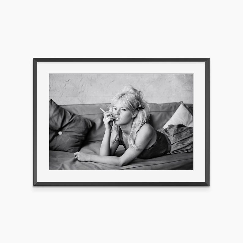 A black and white photograph of a woman lying on a couch, looking pensive.