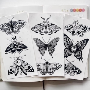 May include: Black and white moth and butterfly illustrations on paper. The drawings feature intricate details and various wing patterns. The images are displayed on pages within an open notebook, with dates visible at the top.