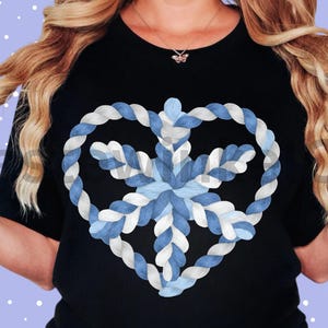 May include: Black crew neck t-shirt with a heart-shaped design made of blue and white rope, with a snowflake in the centre. The design has a winter theme.