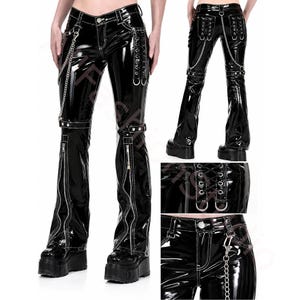 May include: Black vinyl trousers featuring a glossy finish, silver-tone metal chains, and lace-up detailing on the hips. The trousers include vertical zips on the lower legs, contrast white stitching, and metal hardware accents throughout the design.